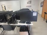 des rangées d'écrans d'ordinateur posés sur les bureaux d'une salle de classe