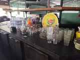 de nombreux verres posés sur le comptoir d'un restaurant où se trouvent de nombreuses bouteilles