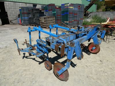 a blue plow that is sitting in the dirt