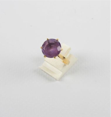 gros plan d'un anneau de pierre violette sur une surface blanche