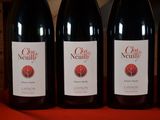 four bottles of red wine are lined up on a table
