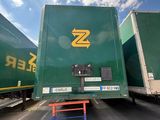 two green semi trucks parked next to each other in a parking lot
