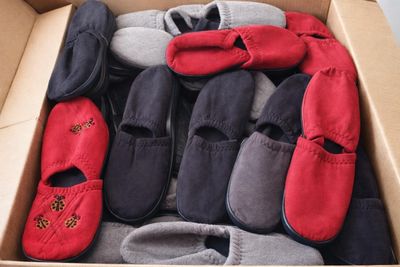 de nombreuses paires de pantoufles dans une boîte posée par terre