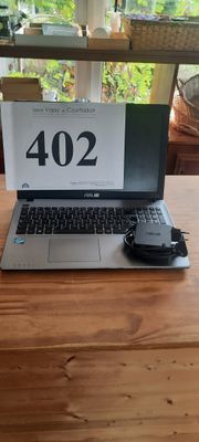 un ordinateur portable posé sur une table en bois, avec une souris à côté