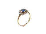 gros plan d'une bague en or avec une pierre bleue