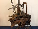 une sculpture métallique représentant un oiseau perché sur une charrette