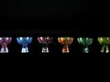 six vases en verre de couleurs différentes alignés sur un fond noir