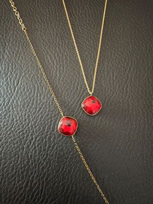 a pair of red and gold necklaces on a black leather surface