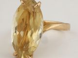 a close up of a yellow gold ring with an oval cut citrine stone