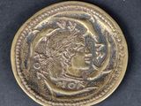 a close up of a gold coin with a woman ' s face on it