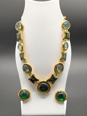 un ensemble collier et boucles d'oreilles vert et or posé sur un mannequin