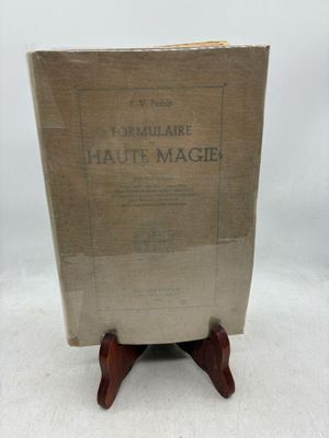 un vieux livre posé sur un support en bois, sur une surface blanche