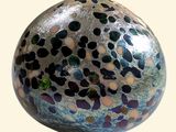a blue, green, and black speckled egg on a white surface