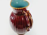 a red vase with a blue top on a white surface