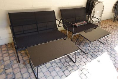 two black chairs and a table on a brick patio