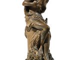 an antique bronze statue of a woman sitting on a rock