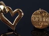 deux pendentifs en forme de cœur dorés posés sur une surface noire, sur fond noir