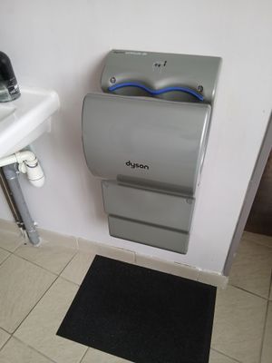 une salle de bains équipée de toilettes, d'un lavabo et d'un distributeur de papier accroché au mur