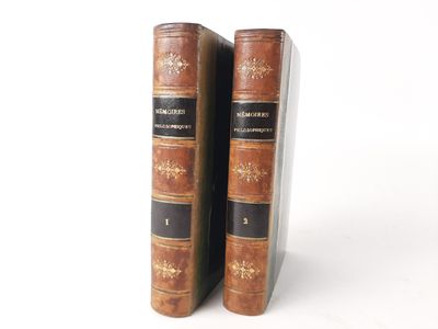 two old books are sitting on a white surface next to each other