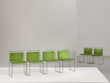 four green chairs sit on a white platform in a white room