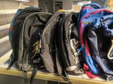 a pile of backpacks sitting on a shelf in a room
