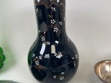 a black vase sitting on top of a table next to other decorative items