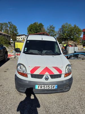 une camionnette blanche garée sur un parking, avec une bande rouge et blanche à l'avant