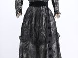a black dress on a mannequin stand with a white background