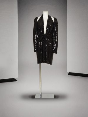 une photo d'une veste noire à paillettes posée sur un présentoir pour mannequin