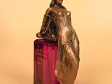 statue of a woman holding a bottle of perfume on a yellow background