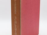 a red book with a brown cover sitting on top of a white table
