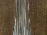 un vase en verre transparent posé sur une table, avec un mur marron en arrière-plan