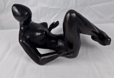 une statue noire représentant une femme allongée sur un drap blanc