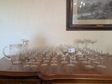 de nombreux verres à vin posés sur une table, avec un tableau accroché au mur en arrière-plan