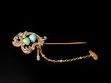 a close up of a gold broochle with a turquoise stone on it