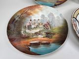 three decorative plates with a painting of people on them on a table