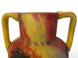 a colorful vase with a yellow handle on a white surface