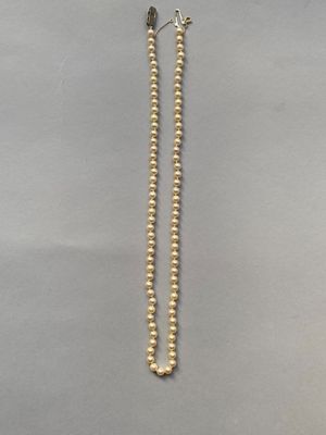 un gros plan d'un long collier de perles posé sur une surface grise