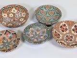 six bowls with designs on them sitting on a white surface