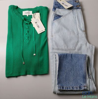 deux paires de jeans et un pull posés sur une table