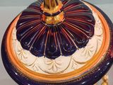 a blue and orange vase with a lid on a stand