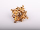 a close up of a gold broochle with pearls on it