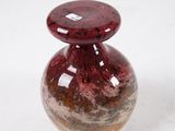 a red vase that is sitting on a white surface