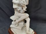 une statue blanche représentant une femme assise sur un livre