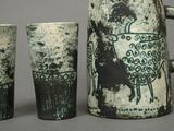 three cups and a jug sitting next to each other on a table