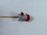 a small piece of jewelry on a stick on a white surface