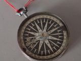 a compass with a red string hanging from it
