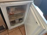 a small white refrigerator with its door open on a tiled floor