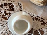 a white cup and saucer sitting on a doily on a table