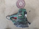 a corded sander on the ground next to a disc